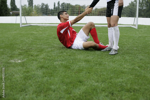 Soccer player helping a opponent standing up