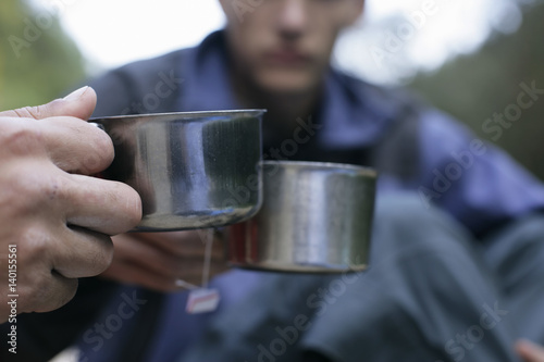 Young men clinking glasses with metallic teacups, selective focus © Gudrun