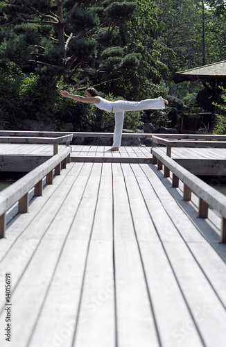Woman doing a Yoga-Exercise on a wooden Footbridge - Trees - Nature - Harmony