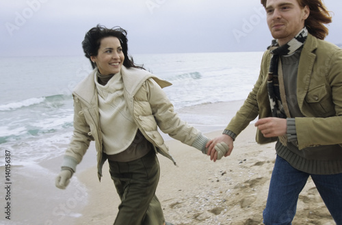 Canvas Print Young brownhaired Woman going for a Walk at the Beach with her Boyfriend - Happi