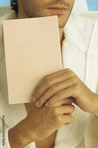 Man in a Bathrobe with a Three-Day Beard holding a Book in his Hand - Print Media - Leisure Time