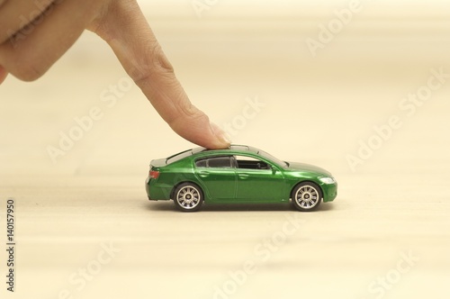 Finger pushing green toy car