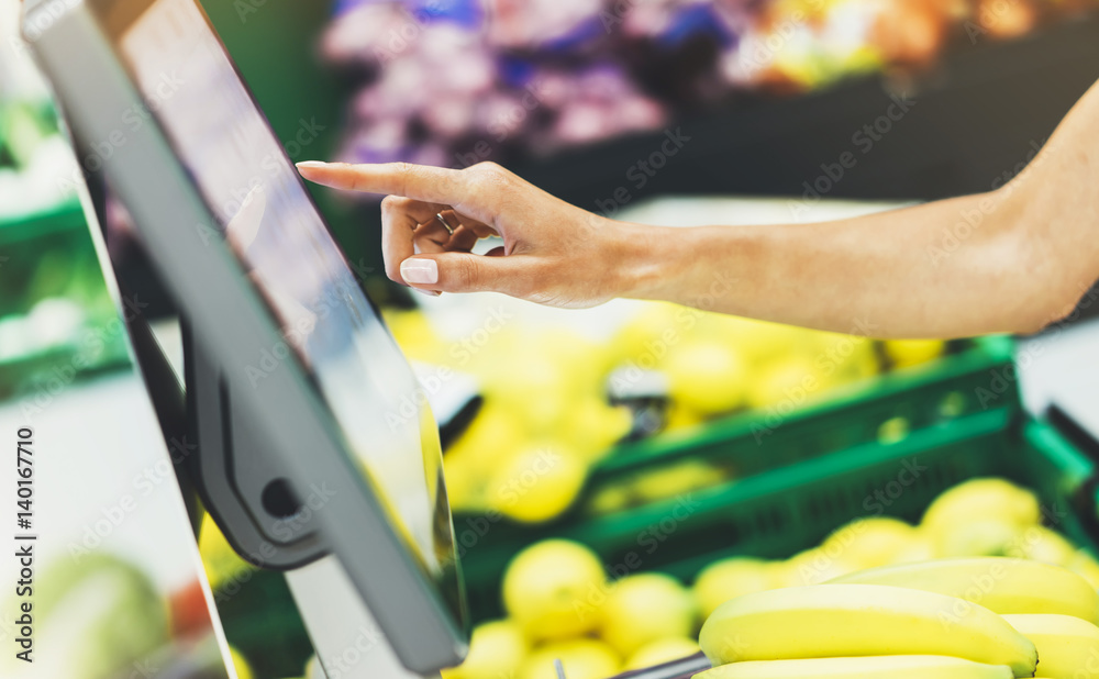 buyer weighs the yellow bananas and points the fingers on the screen electronic scales, woman shopping healthy food in supermarket blur background, female hands buy nature products in store grocery