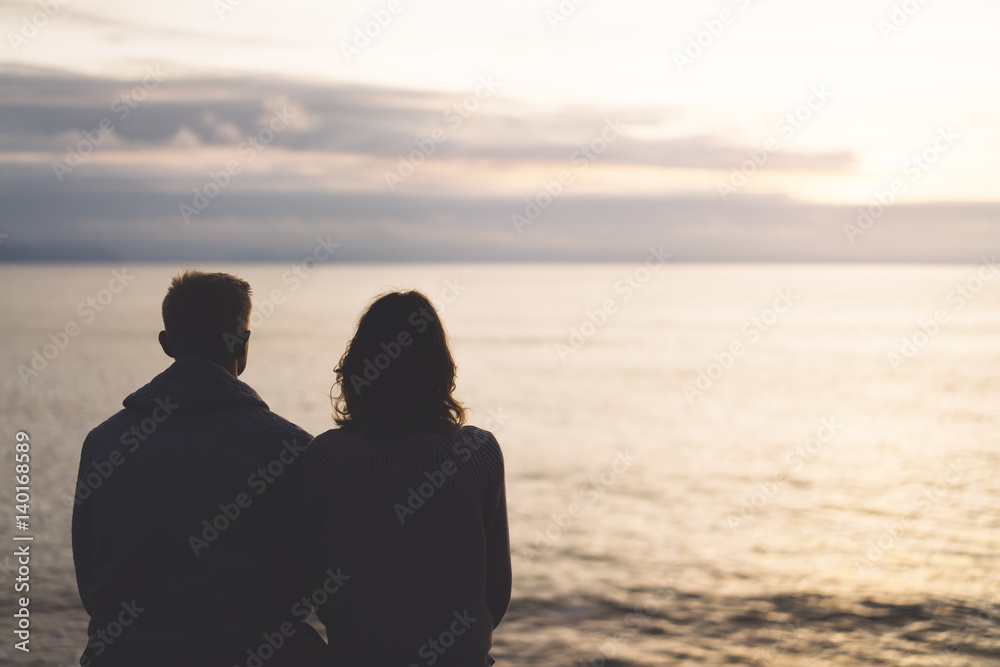 Couple hugging on the beach on background ocean sunrise, silhouette two romantic people cuddling and looking on rear view evening seascape, hipster enjoy  sunset together, travel holidays vacation