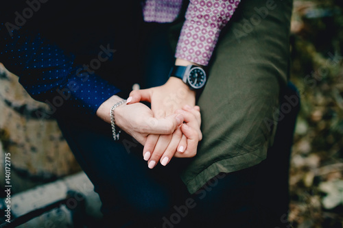 guy with a watch on his arm holds the girl's hand. Lovers. The dark background. © Parilov