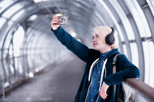 Young student listening to music in big headphones in the subway tunnel