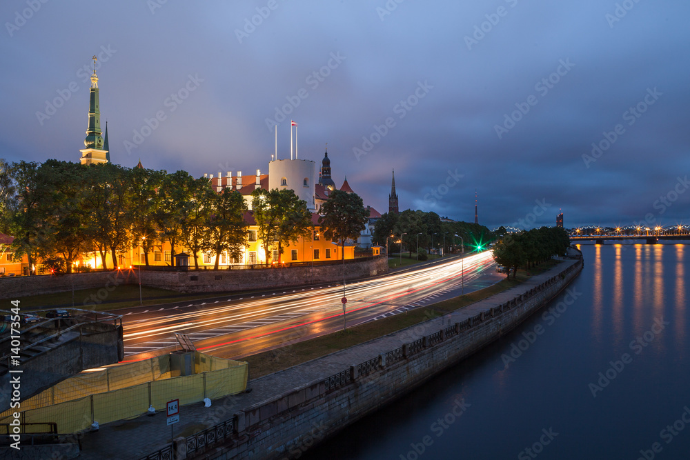 Fototapeta premium Night scene with traffic, old town and river bank in Riga, Latvia