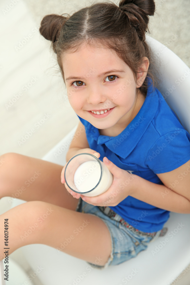 Little girl sitting on chair with glass of milk Little girl sitting on chair with glass of milk