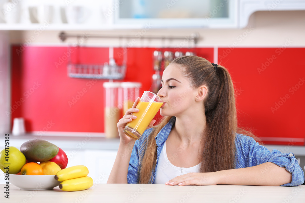 Young beautiful  woman  in kitchen drinking juice