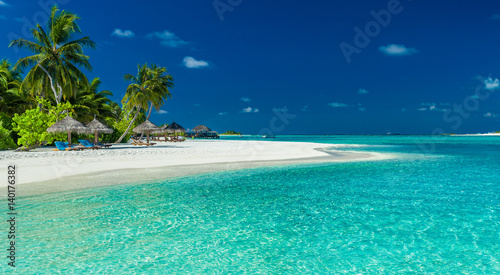 Fototapeta Naklejka Na Ścianę i Meble -  Palm trees and beach umbrelllas over lagoon and white sandy beach, Maldives
