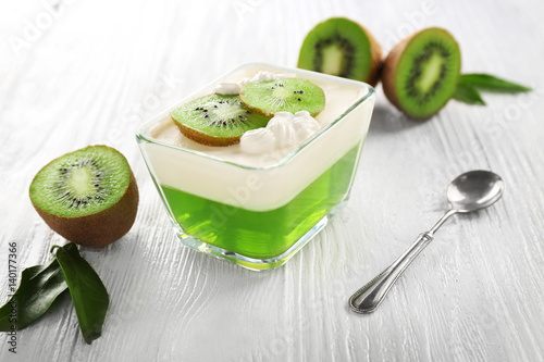 Tasty jelly dessert with kiwi and cream on wooden table