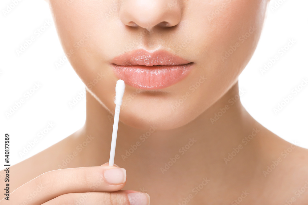 Woman touching lips with cotton swab on white background