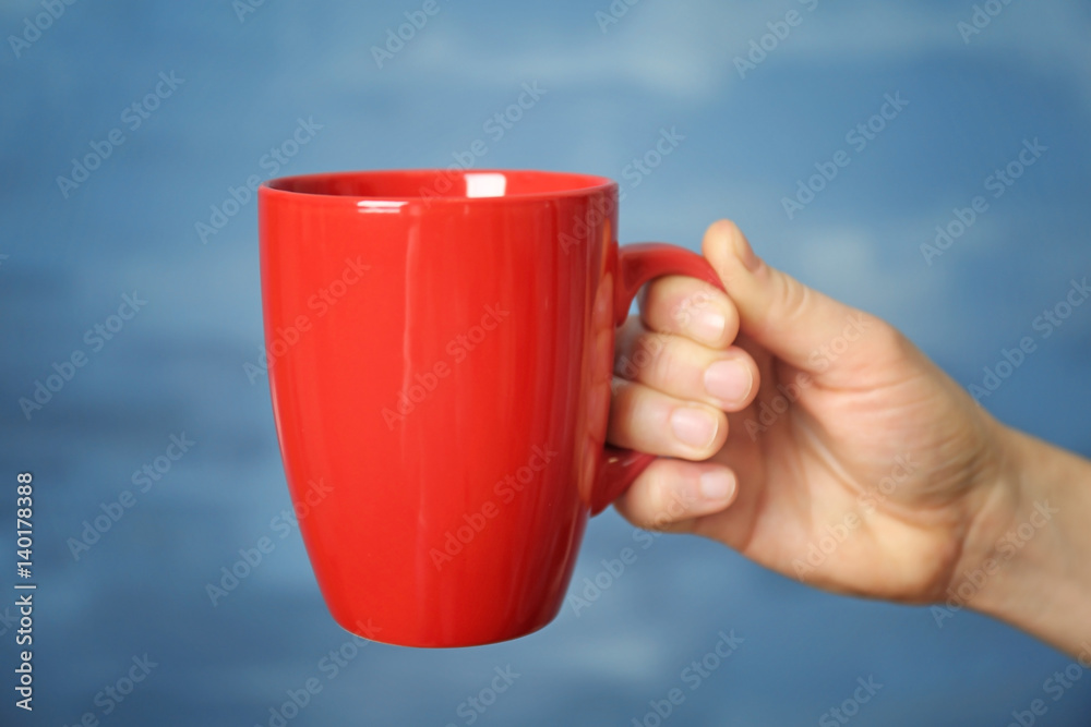 Obraz premium Blank red cup in hand, closeup