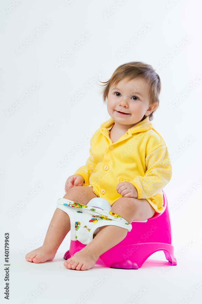 Little smiling girl sitting on a pot. Isolated on white background. Little smiling girl sitting on a pot. Isolated on white background.