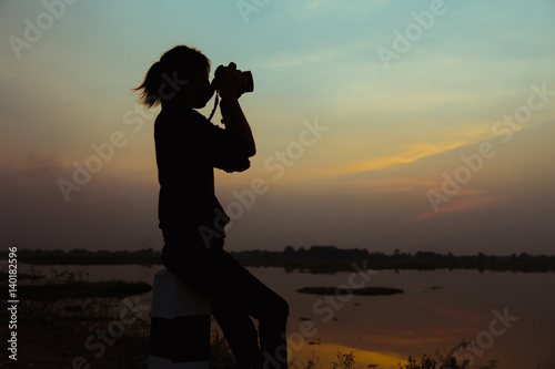 Silhouette women Nature photographer with digital camera on the mountain and lake