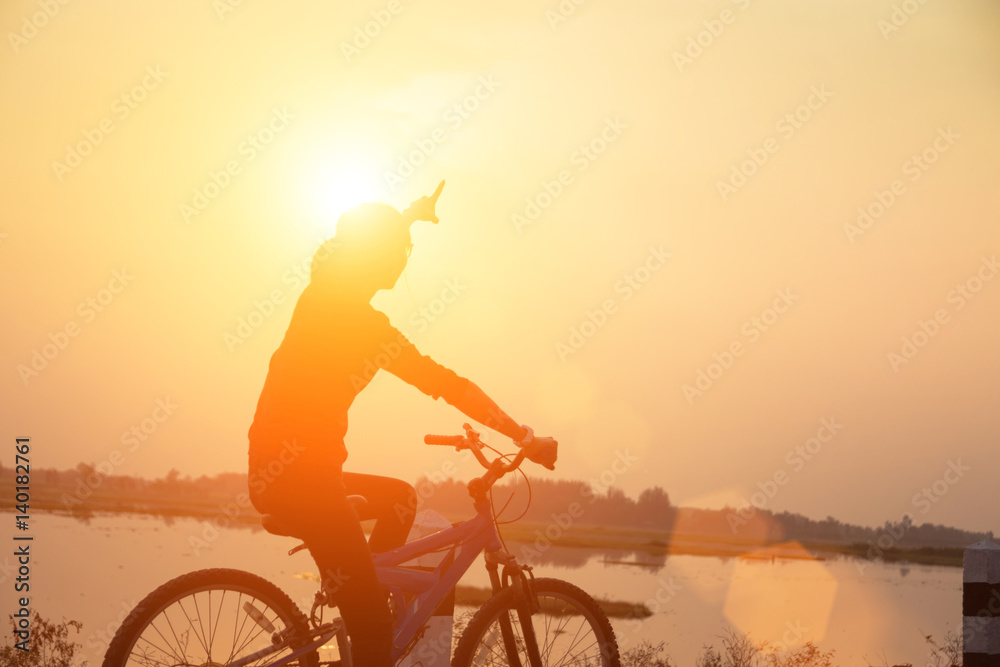 Obraz premium Silhouette biker-girl at the sunset on the meadow