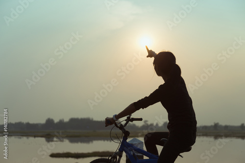 Fototapeta Naklejka Na Ścianę i Meble -  Silhouette biker-girl at the sunset on the meadow