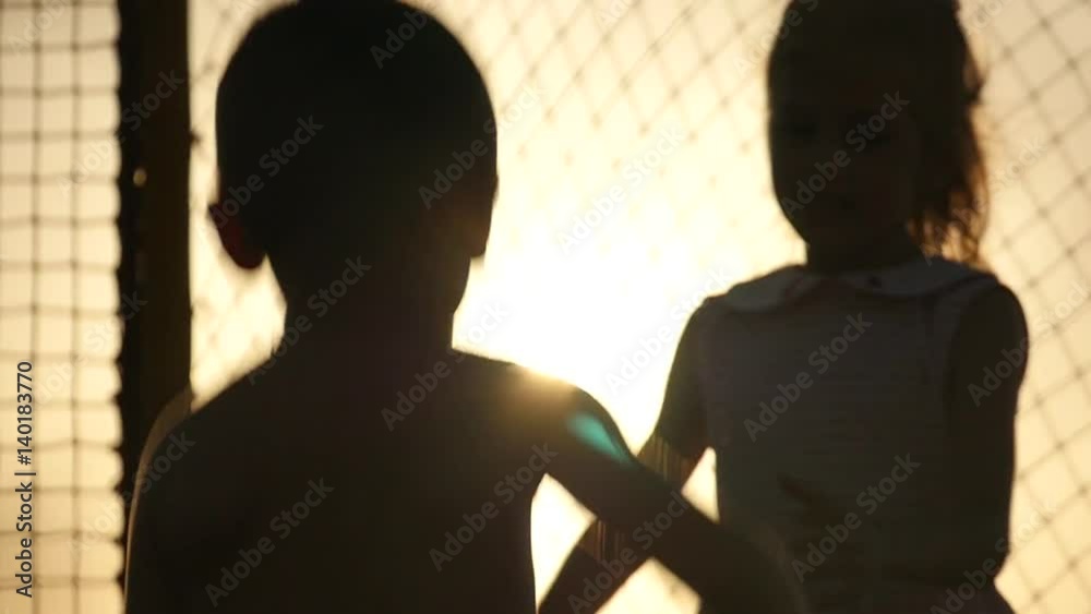 cute boy and girl jumping on the trampoline in the sunset cute boy and girl jumping on the trampoline in the sunset