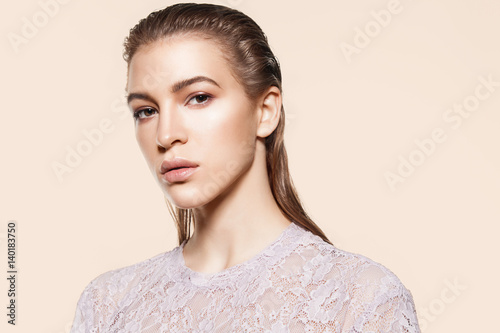 Portrait of a stylish woman model with natural make-up and wet hair on a beige background in lacy clothes