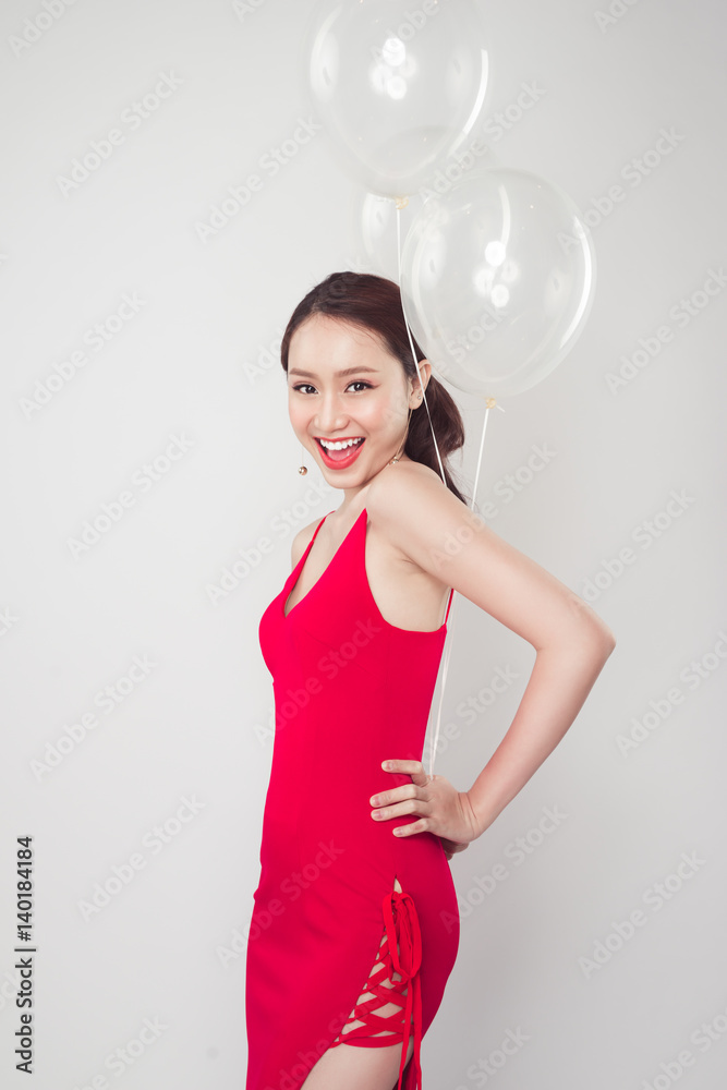 Pretty young asian woman wearing red dress with balloons in hand. Pretty young asian woman wearing red dress with balloons in hand.