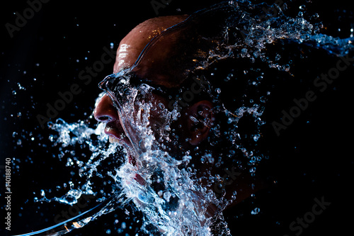 Portrait of a man being thrown water in the face against a black background