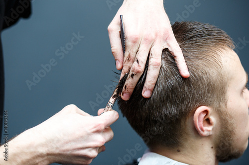 Great time at barbershop. Cheerful young bearded man getting haircut by hairdresser while sitting in chair at barbershop