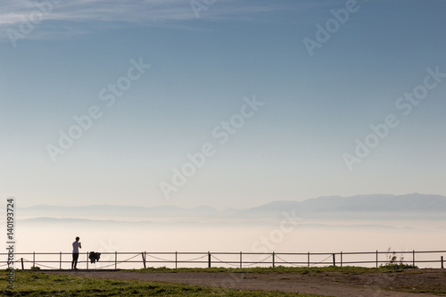A man looking at a sea of fog under a big, clear sky