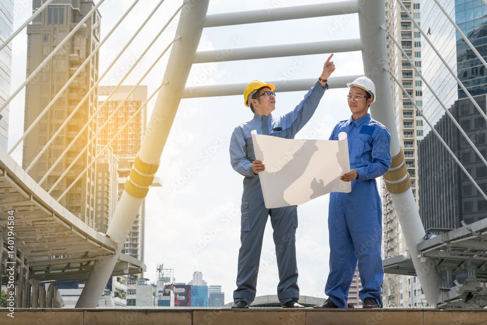 Engineer and Architect working at Construction Site with blueprint