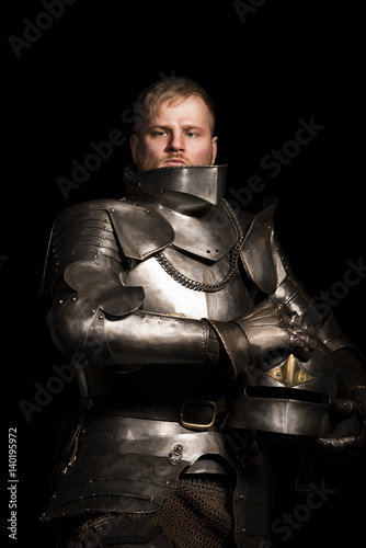 Knight in armour after battle on the black background
