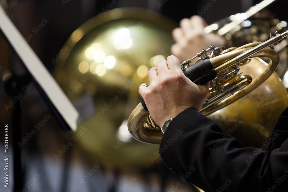 Obraz premium French horn in the hands of a musician in the orchestra closeup in dark colors