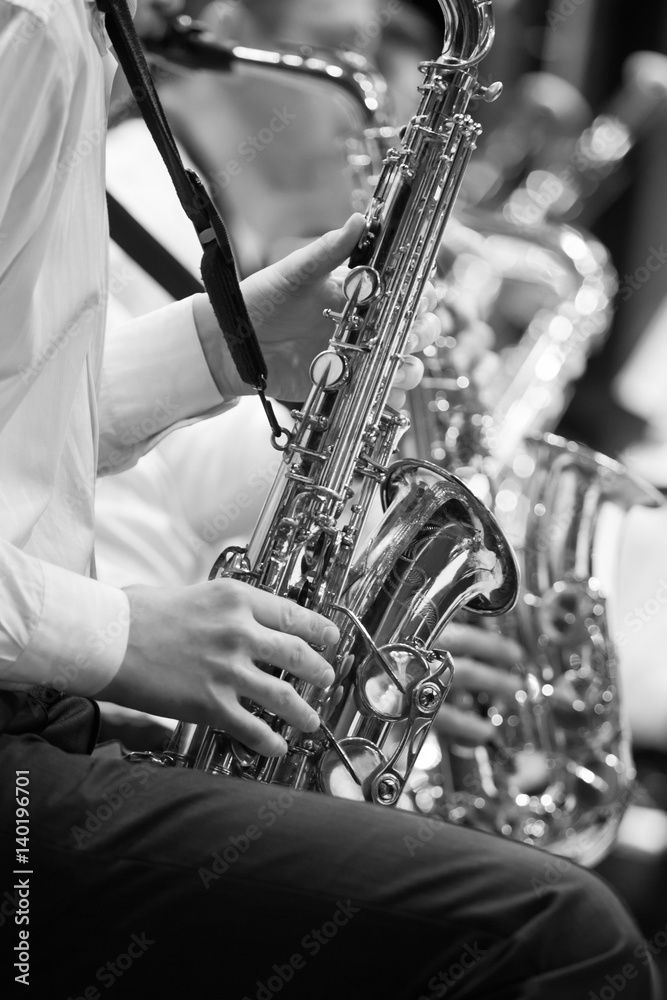Obraz premium Saxophone in the hands of a musician in an orchestra in black and white