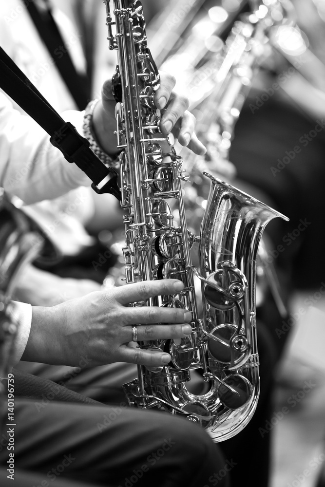 Obraz premium Saxophone in the hands of a musician in an orchestra in black and white