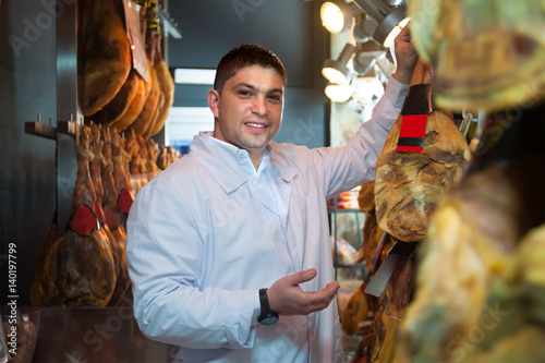 Midle aged butcher hanging wurst and jamon joints photo