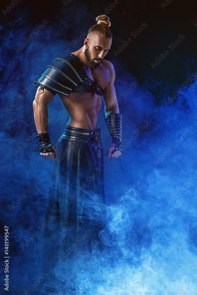 Obraz premium Young and muscular man performing a theatrical pose on stage.