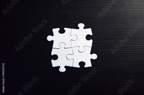 Vier zusammenhängende Puzzleteile auf schwarzem Grund
