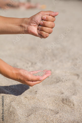 Sand running through female hands.Young woman with sand in her hands. Sand as © goodmoments