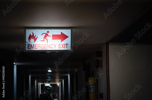 emergency exit sign light showing way to escape in dark path way at night time