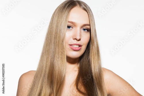 Blonde smiling model woman with long shiny hair and healthy skin looking at camera on white background