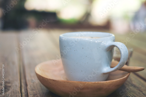 A blue cup of hot Latte coffee on vintage wooden table and blur background 