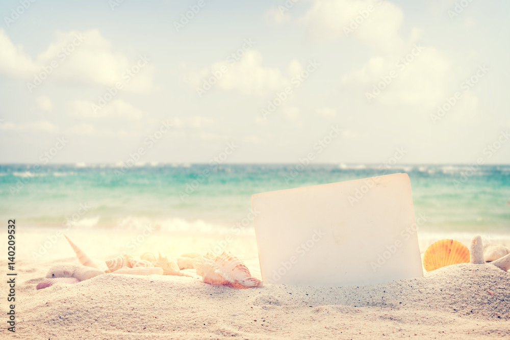 Vintage summer beach background with sand, shells and empty paper for your message design. Concept of summertime relax on beach.