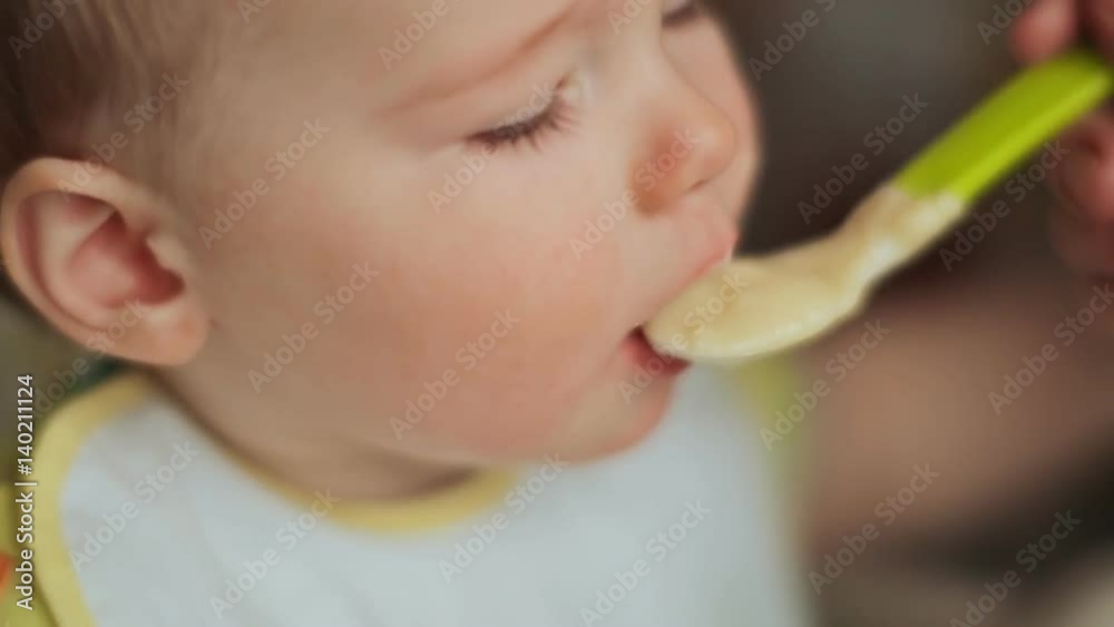 Mother feeds her capricious child. The child refuses to eat porridge and eats waffles. Face close-up. Mother feeds her capricious child. The child refuses to eat porridge and eats waffles. Face close-up.