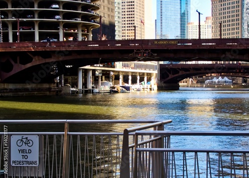 Chicago River in background with "Yield to Pedestrians" bicycle sign in foreground.