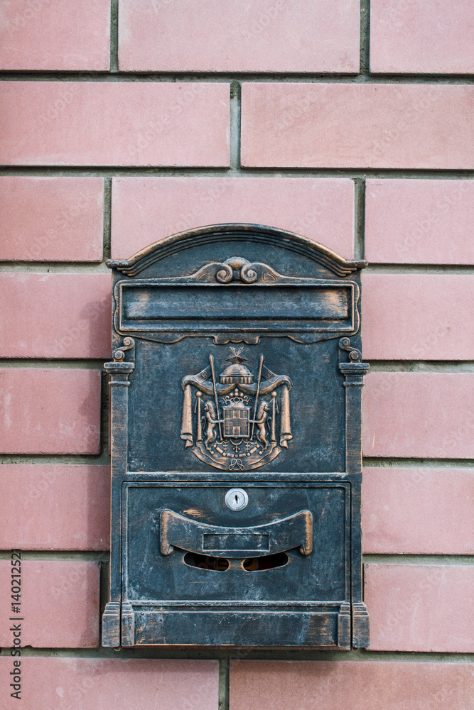 On a brick wall hanging metal mailbox with a picture
