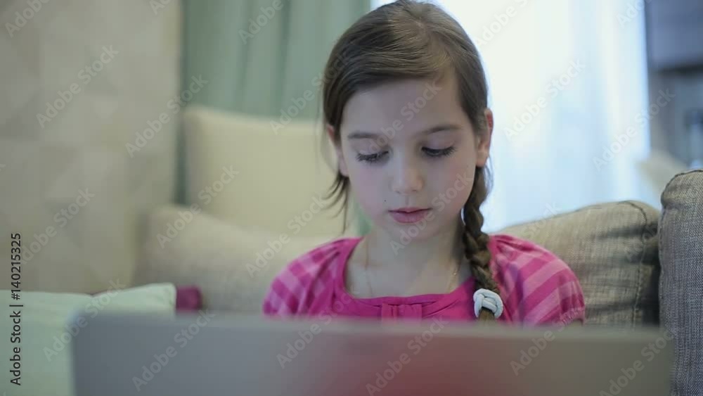 A girl on the sofa is education on a laptop A girl on the sofa is education on a laptop