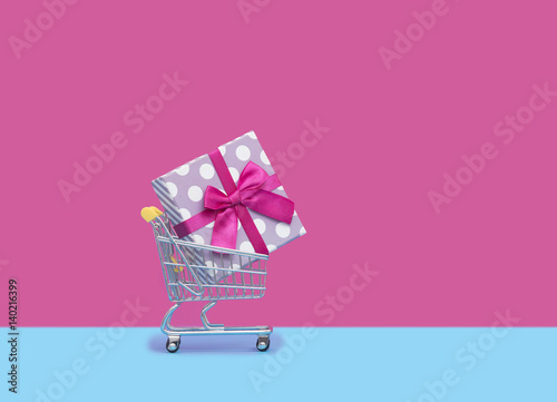 cute pink gift in cool shopping cart in front of the wonderful pink background