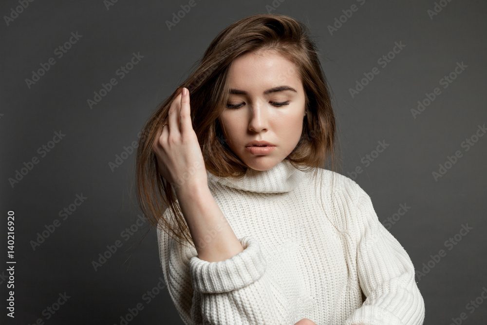 Girl model in white sweater on a gray background. Girl model in white sweater on a gray background.