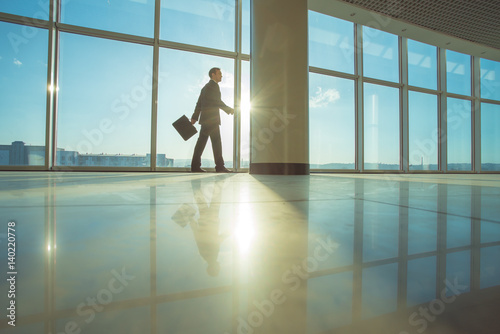 The businessman walk with a suitcase in the office hall