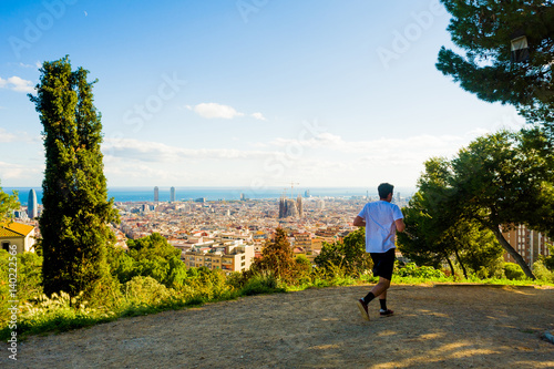 Canvas Print young man jogging with view of barcelona and sagrada familia in summer day