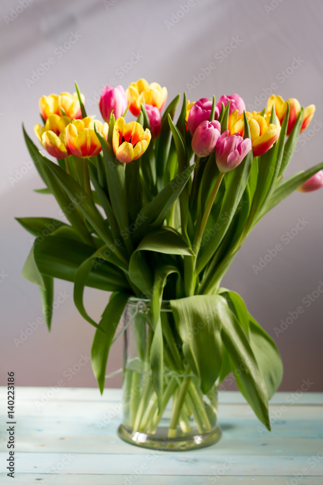 Colorful tulips in glass vase. White background. Colorful tulips in glass vase. White background.