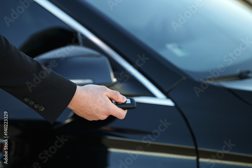 Young man opening his car door with the control remote key © Drobot Dean